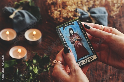 Fototapeta Wiccan witch holding a small hand painted (made up) Hermit tarot card in her hands