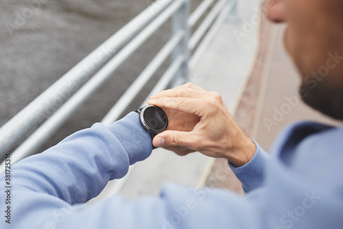 Close-up of young man watching the time on his watch standing outdoors