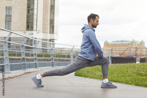 Young athlete doing stretching exercises outdoors he warming up before jogging