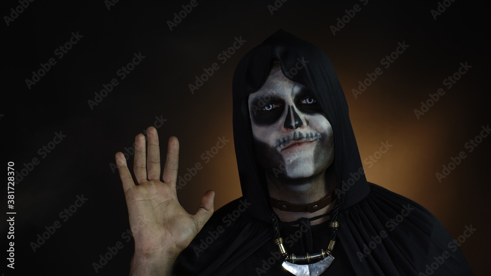 Frightening man in skeleton Halloween costume waving hands looking at camera. Hi, hello, greeting Frightening man in skeleton Halloween costume waving hands looking at camera. Hi, hello, greeting