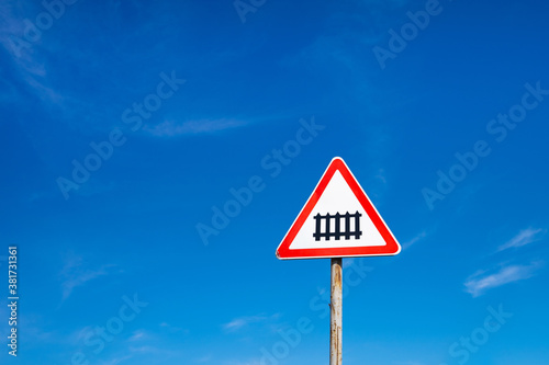 A road sign warning of approaching a railway against a blue sky