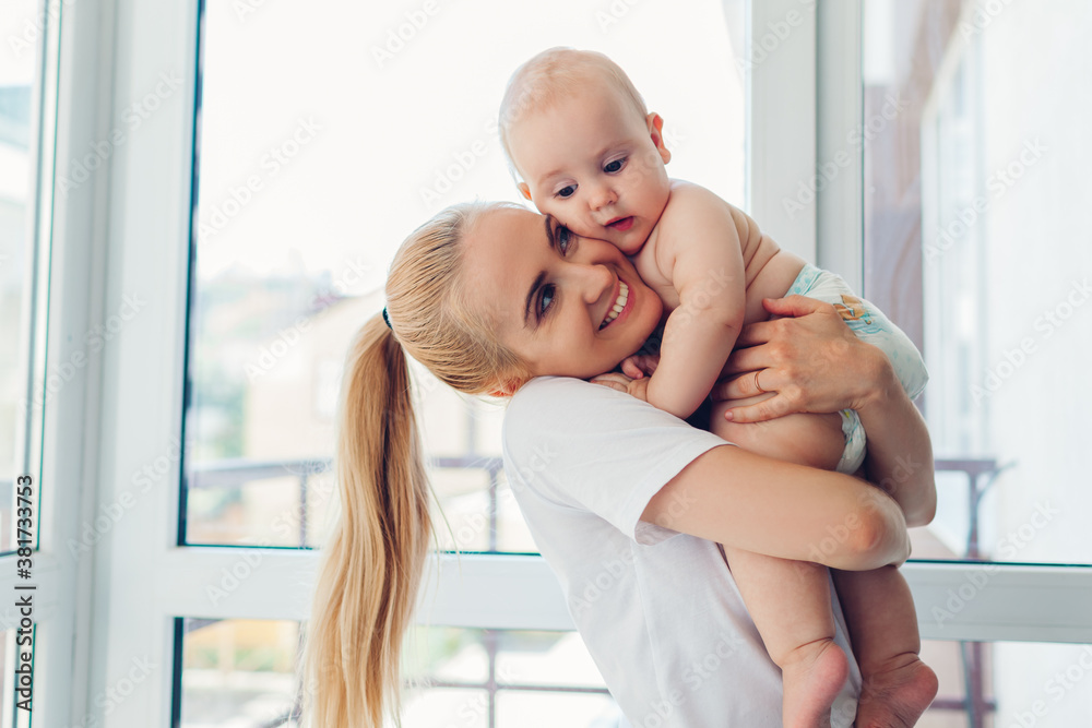 Young mother holding and hugging newborn baby son at home. Family relaxing on balcony. Infant wearing diaper Young mother holding and hugging newborn baby son at home. Family relaxing on balcony. Infant wearing diaper
