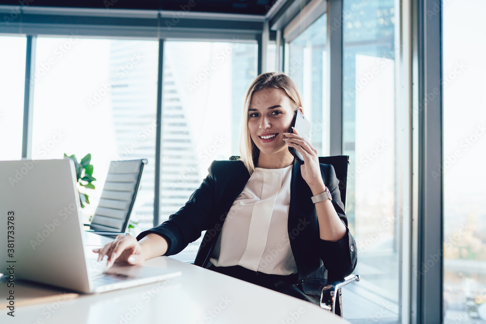 Delighted businesswoman speaking on smartphone and typing on laptop Delighted businesswoman speaking on smartphone and typing on laptop