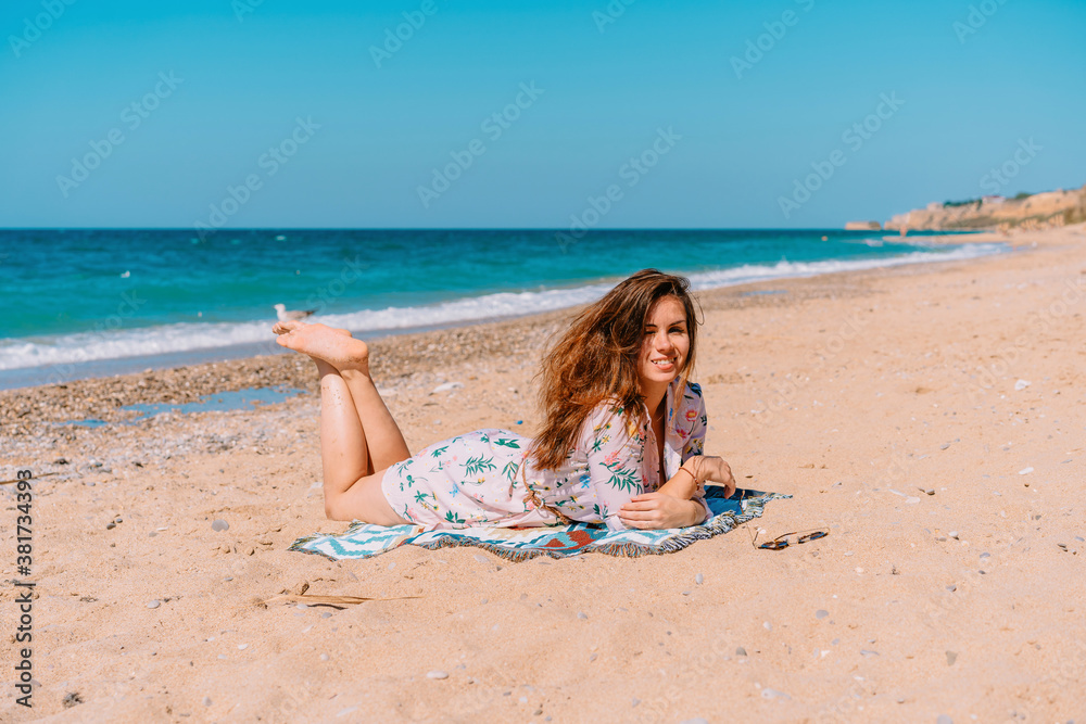 Young woman in sunglasses and dress lying on the beach in front of the sea Young woman in sunglasses and dress lying on the beach in front of the sea