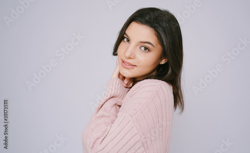 Side view of Portrait of young woman wearing knitted sweater pink cold and looking at camera isolated over grey wall background. Woman beauty treatment perfect skin care concept.