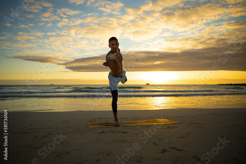 Man practicing yoga on the beach during sunrise sunset