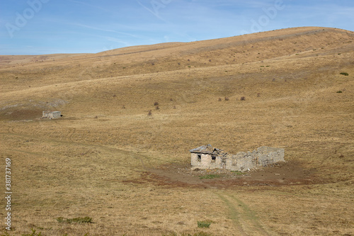 Sad, ruined, abandoned animal farm on the endless grassy highlands of Old mountain