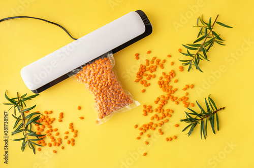 Plastic sealing machine. Vacuum packing of fresh sea buckthorn berries. Long-term storage of products. photo