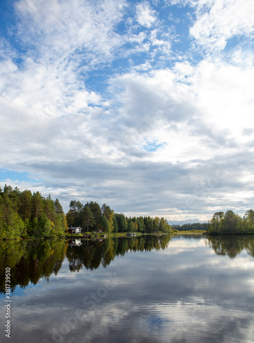 Beautiful landscape in Finland at the lake shore. Reflecting waters and cloudy sky. Calm scenery for poster and wallpaper use.