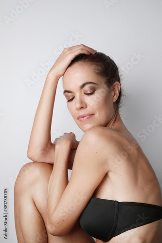 Vertical close-up of attractive middle aged woman touching her head, mature beauty concept.