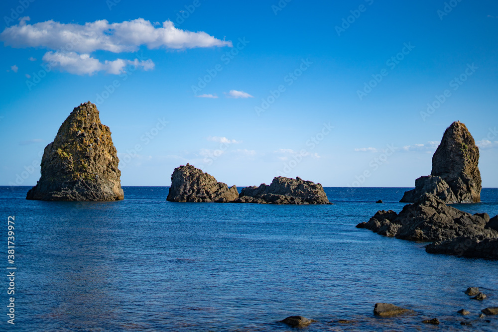 The cliffs of Cyclops (Faraglioni dei Ciclopi) in the sea near Aci Trezza town, Sicily, Italy. summer light day