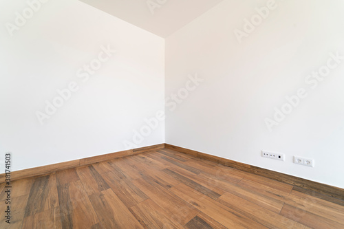 Empty room with dark wooden floating laminate flooring. House interior  wide bedroom or living room space. Newly recently painted new apartment or house. Wood floor. Real state and property management