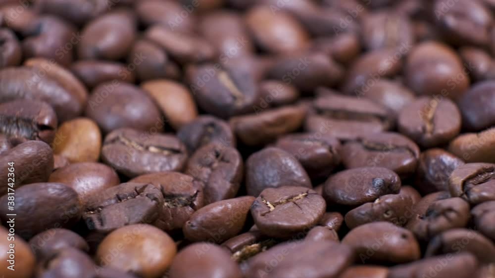 Closeup of dark roasted coffee beans on rotating table. Aromatic coffee grains are turning. Closeup of dark roasted coffee beans on rotating table. Aromatic coffee grains are turning.