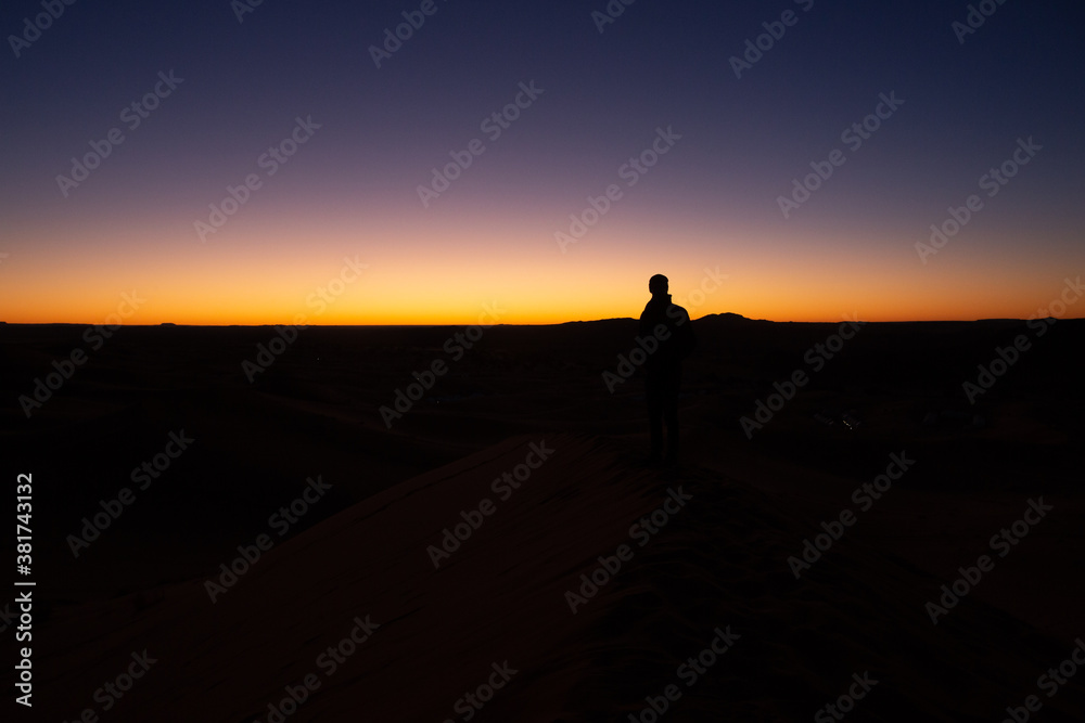 A person contemplates during sunset in the desert