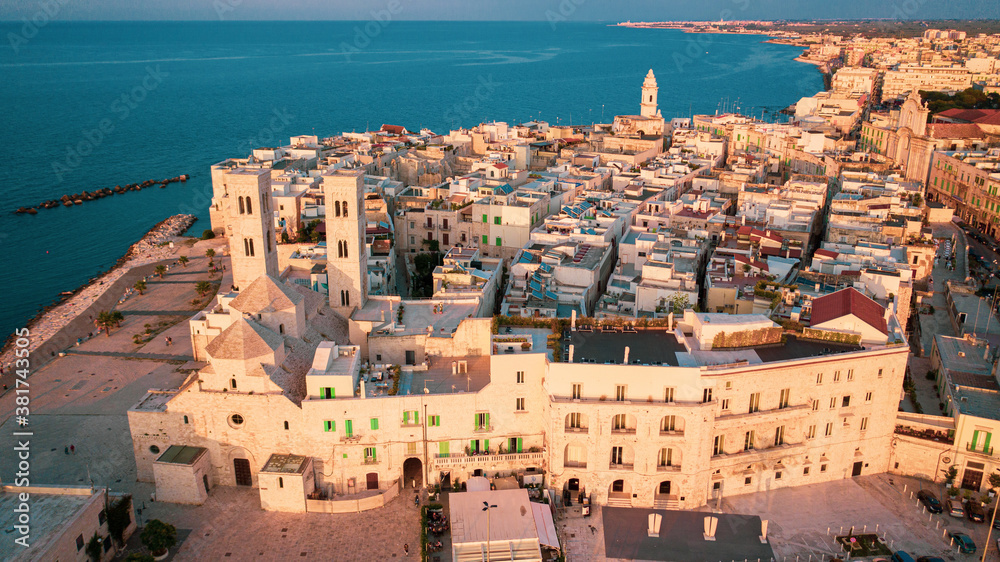 Beautiful panoramic aerial view photo from flying drone on Molfetta waterfront with the Old Cathedral San Corrado (Duomo Vecchio),port with ships and yachtsand the Molfetta city sunset. Apulia ,Italy