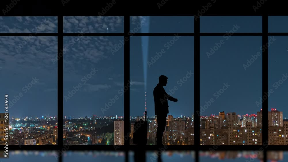 The man with suitcase stands indoors on the night urban background. time lapse The man with suitcase stands indoors on the night urban background. time lapse