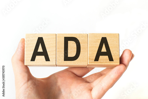 Hand holds wooden cubes with letters ADA. Business concept image.