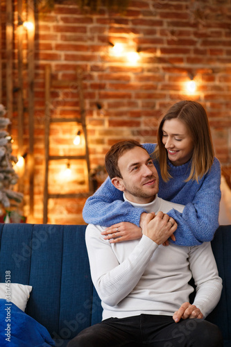 Portrait of beautiful smiling couple hugging at Christmas eve. Beautiful young couple at home enjoying spending time together. Winter holidays, Christmas celebrations, New Year concept.