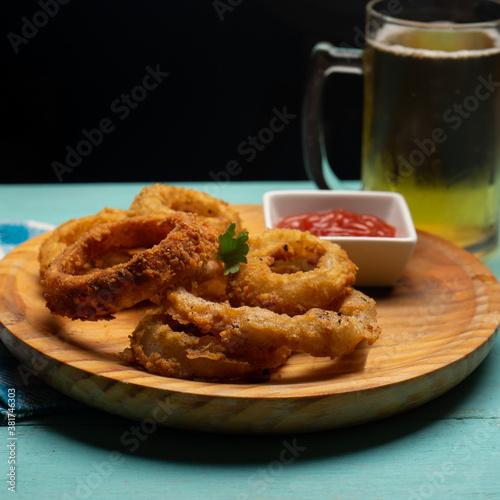 Onion rings with ketchup on turquoise background