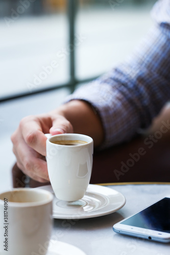 Businessman sitting in cafe  drinking morning coffee and using smartphone