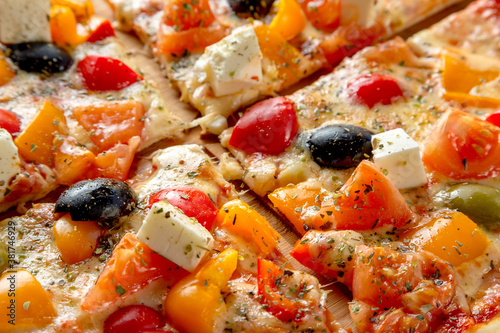 Greek pizza with olives, bell peppers, feta cheese and tomatoes.