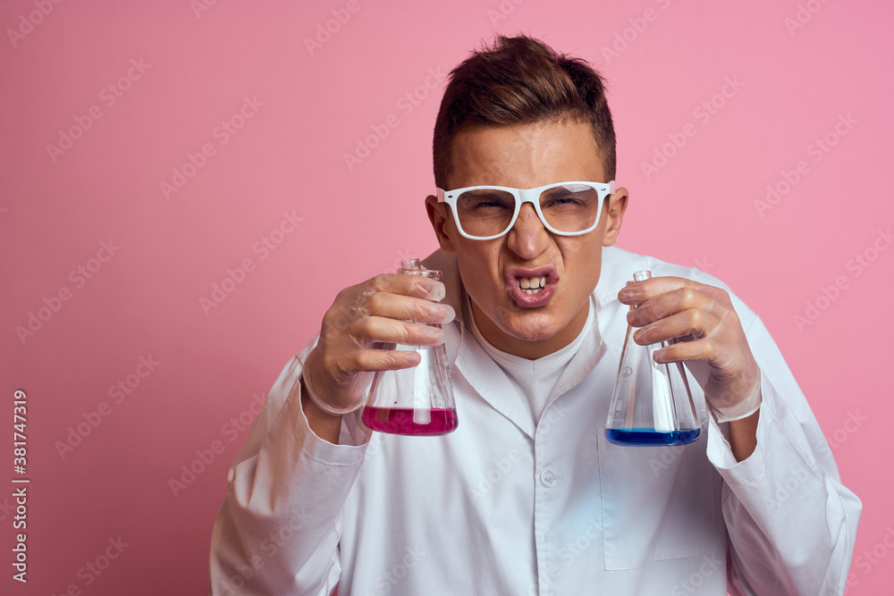Male laboratory assistant with flasks in the hands of a multicolored liquid chemical substance Male laboratory assistant with flasks in the hands of a multicolored liquid chemical substance