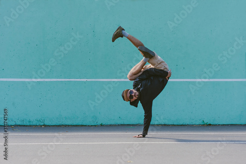 BBOY dancing breakdance against a blue wall.