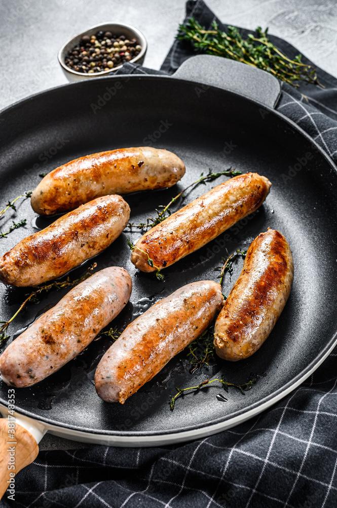 Grilled assorted pork, beef and chicken sausages with spices in a pan.  Gray background. Top view