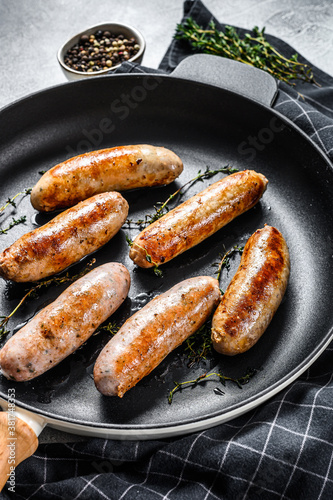 Grilled assorted pork, beef and chicken sausages with spices in a pan. Gray background. Top view