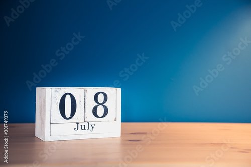 July 8 - white calendar blocks on wooden table against vintage blue background