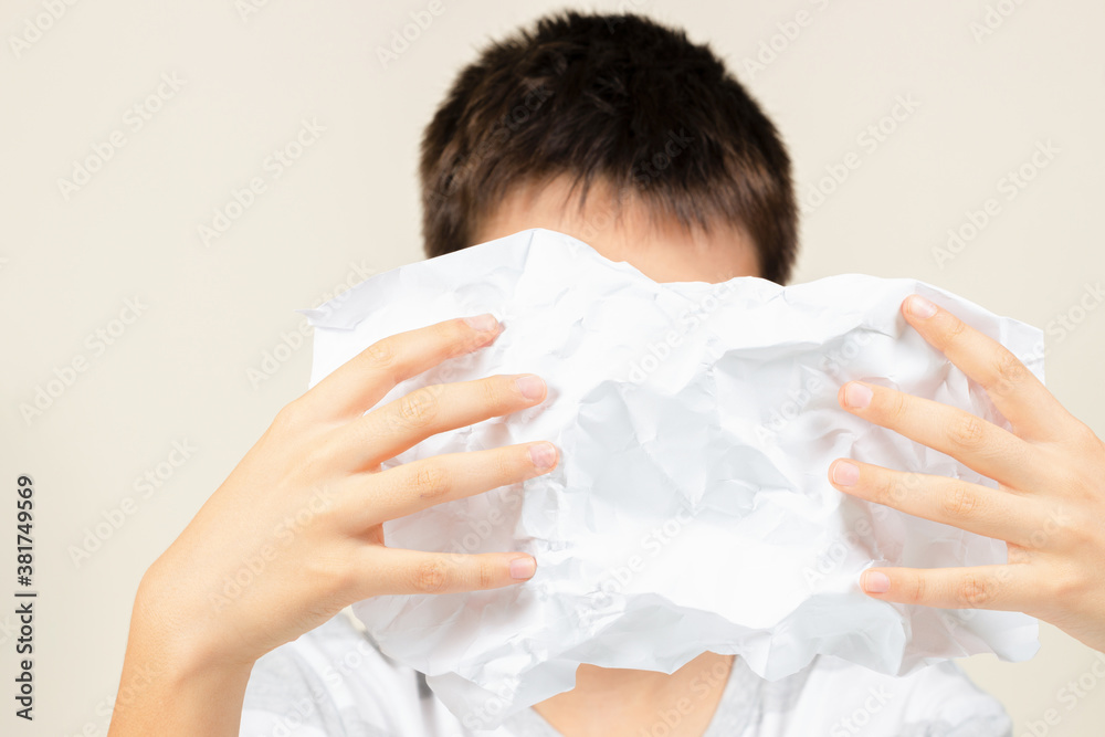 Sad disappointed kid crumpled sheet of paper and hiding his face Sad disappointed kid crumpled sheet of paper and hiding his face