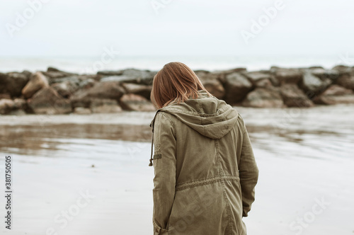 Young girl photographed on the beach on a rainy autumn day