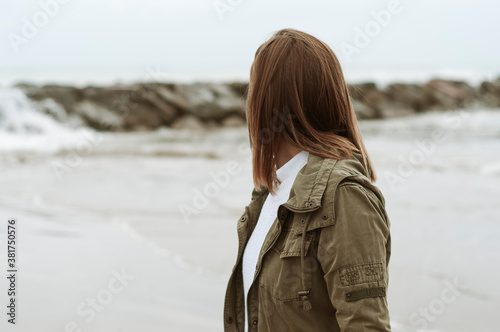 Young girl photographed on the beach on a rainy autumn day