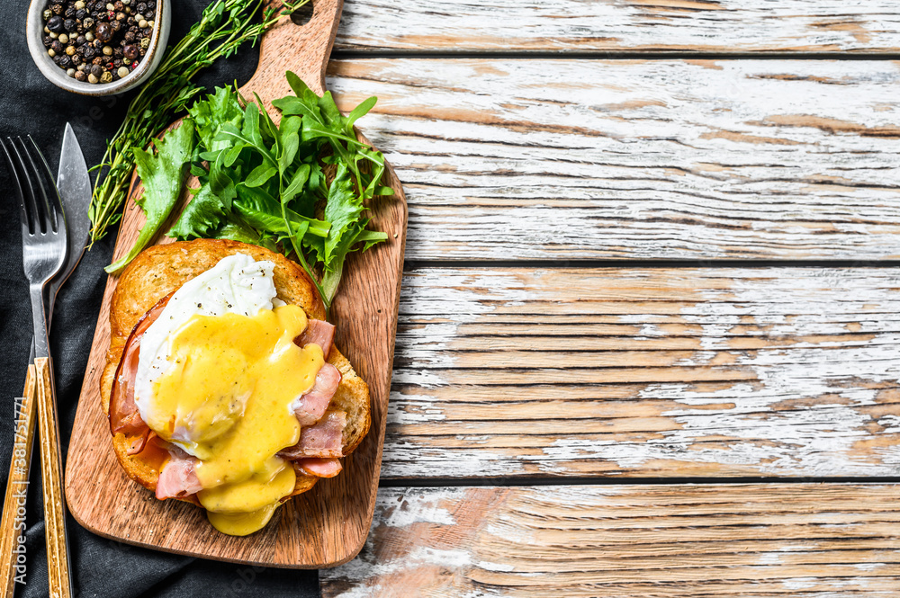 Breakfast Burger with bacon, egg Benedict, hollandaise sauce on brioche bun. Garnish with arugula salad. White background. Top view. Copy space