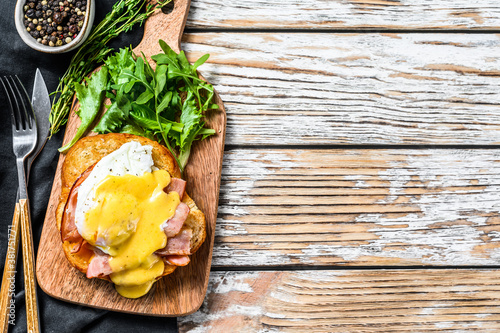 Breakfast Burger with bacon, egg Benedict, hollandaise sauce on brioche bun. Garnish with arugula salad. White background. Top view. Copy space