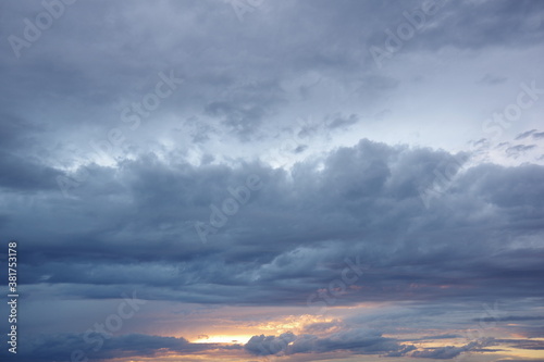 Dark storm clouds with colorful reflections of the setting sun. Scenic storm clouds lit by the last rays of the sunset.