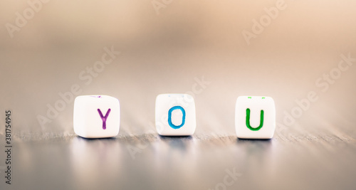 Word YOU on blurred background - colourful letters