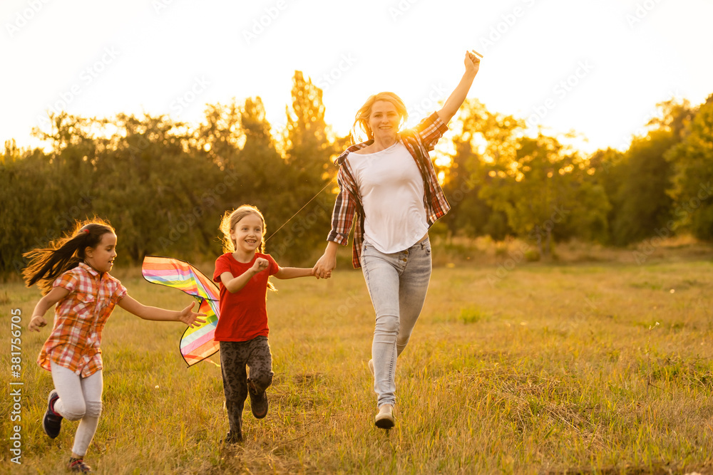 Fototapeta premium happy family mother and children run on meadow with a kite in the summer on the nature