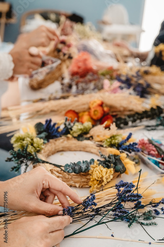 Girl making floral door wreath from colorful dry summer flowers and plants.  Fall flower decoration workshop