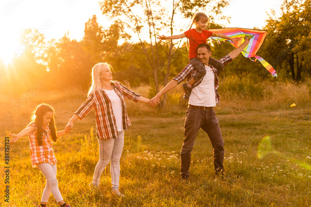 Fototapeta premium Happy family with a kite playing at sunset in the field