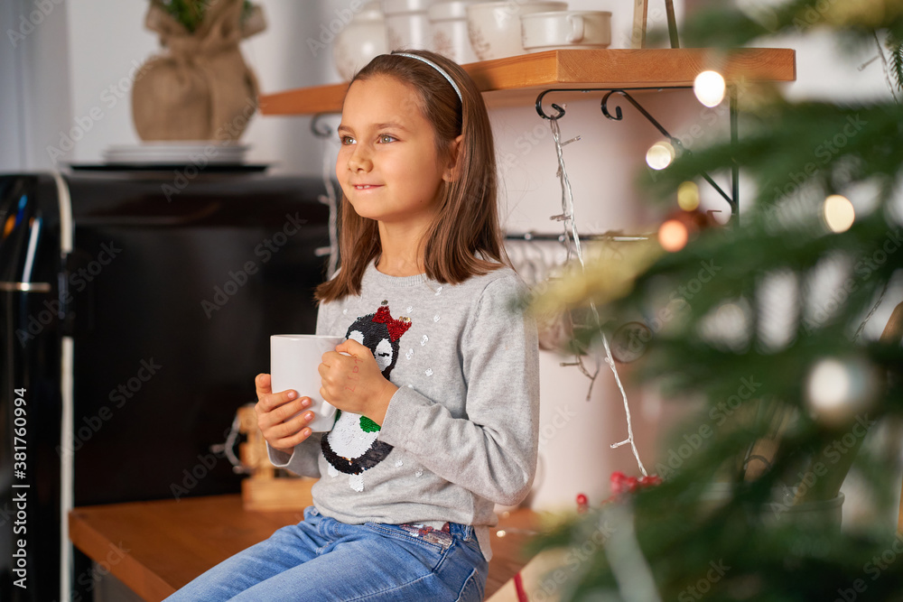 A little girl with a cup of hot tea dreams of a Santa present for Christmas A little girl with a cup of hot tea dreams of a Santa present for Christmas