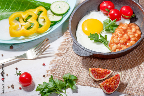 Fried egg in cast iron serving pan, cherry tomatoes, beans and vegetables