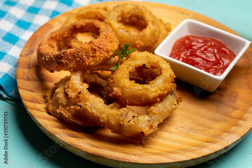 Onion rings with ketchup on turquoise background