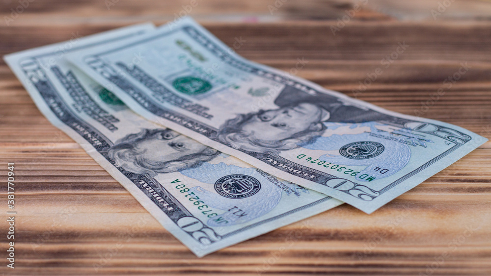 Two 20 US dollars bills lying on a burnt wooden table top. Two 20 US dollars bills lying on a burnt wooden table top.