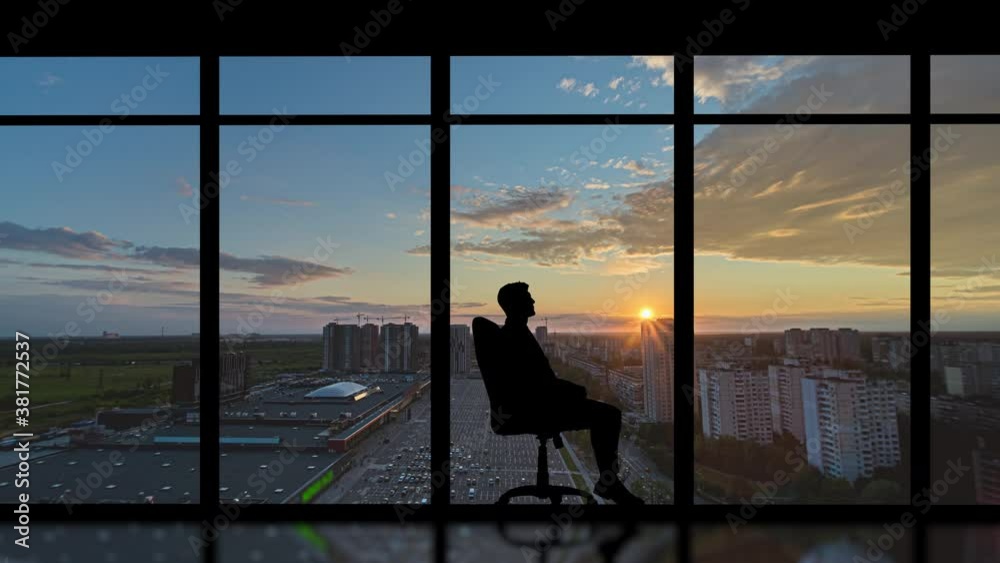 The man sitting in the chair against the morning city background. time lapse The man sitting in the chair against the morning city background. time lapse