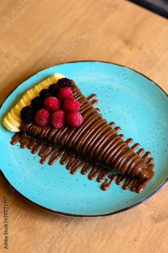  a beautifully decorated caloric pancake full of delicious chocolate. pancake on a plate with many different toppings of chocolate and fruit. fruit pancake.