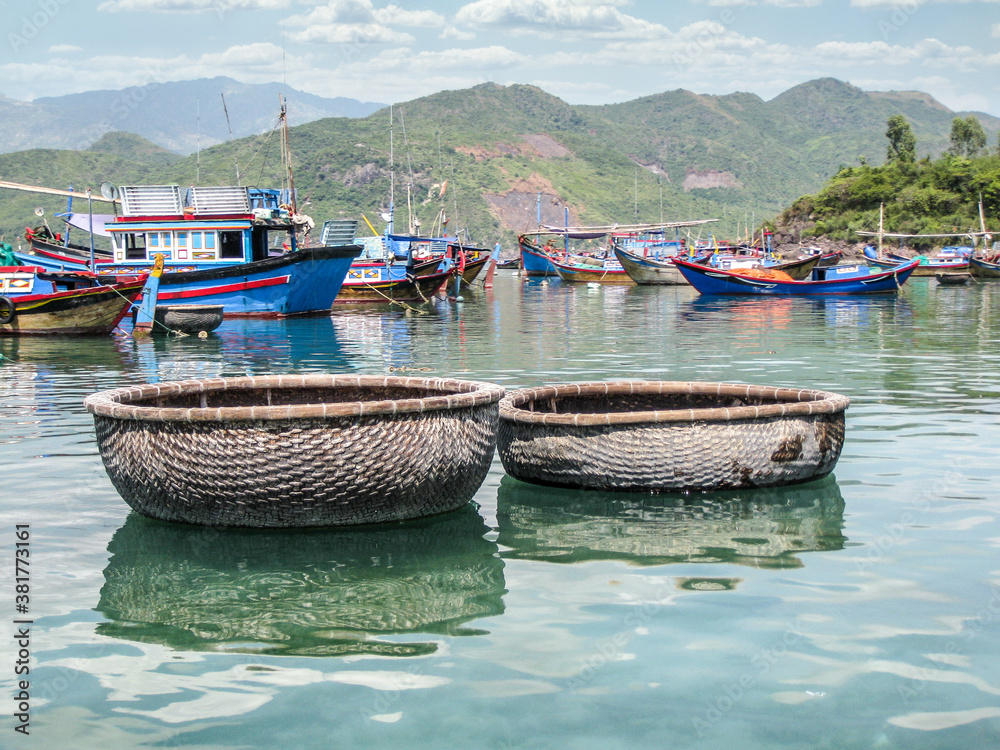 Round, straw boats and colorful fishing boats in Vietnam
