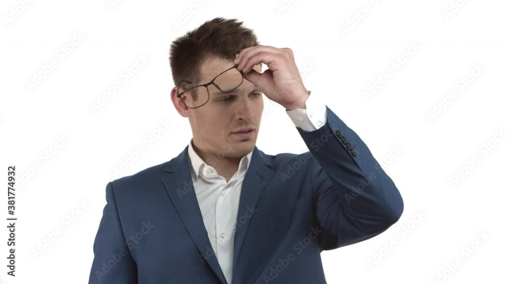 Handsome young businessman in blue suit looking sad, taking-off glasses and shaking head disappointed, upset over failure or losing something, standing over white background Handsome young businessman in blue suit looking sad, taking-off glasses and shaking head disappointed, upset over failure or losing something, standing over white background