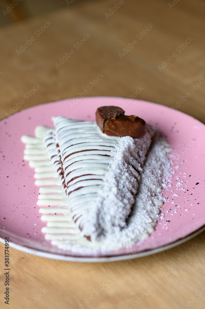 caloric pancake with white topping beautifully served on a pink plate. pancake with chocolate decoration.