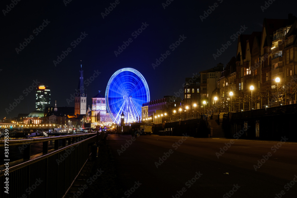Night scenery on promenade along riverside of Rhine river and background of Ferris wheel at Christmas market and cityscape in Düsseldorf, Germany.